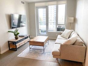 Vancouver condo for rent - A living room with a couch, coffee table, and a flat screen TV mounted on the wall.