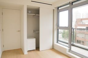 Vancouver condo for rent - A white bedroom with a large window and a white dresser.