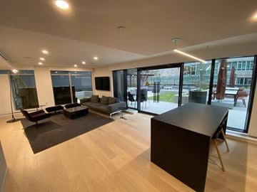 Vancouver condo for rent - A modern living room with a black sofa and a wooden floor.
