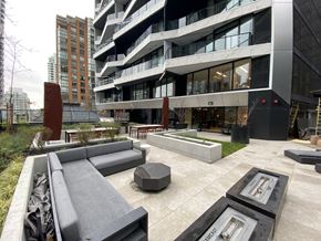 Vancouver condo for rent - A modern outdoor seating area with a bench and a table in front of a building.