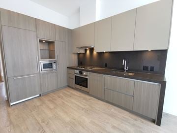 Burnaby condo for rent - A modern kitchen with wooden cabinets and a stainless steel oven.