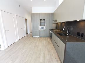 Burnaby condo for rent - A modern kitchen with a wooden floor and a dark counter.