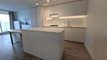 Coquitlam condo for rent - A kitchen with white cabinets and a large island.
