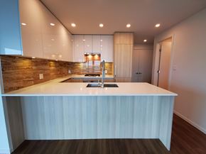 Burnaby apartment for rent - A modern kitchen with a white countertop and wooden flooring.
