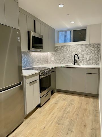 Vancouver apartment for rent - A modern kitchen with a stainless steel refrigerator, microwave, and oven.