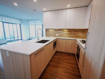 Burnaby apartment for rent - A modern kitchen with wooden cabinets and a white countertop.
