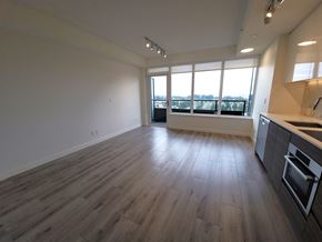 Surrey condo for rent - A spacious room with wooden flooring and a kitchen area to the right.