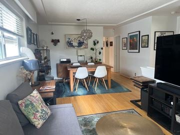 Vancouver triplex for rent - A living room with a grey couch and a wooden dining table.