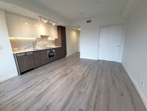 Surrey condo for rent - A spacious room with a kitchen area and a door to another room.