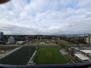 Surrey condo for rent - A view from an airplane window of a green soccer field and buildings in the distance.