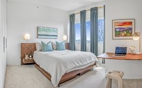 Vancouver apartment for rent - A bedroom with a large bed, a desk with a laptop, and a painting on the wall.