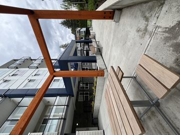 Maple Ridge apartment for rent - A wooden bench is in the foreground of a modern building.
