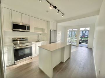 Surrey condo for rent - A modern kitchen with a stove top oven and microwave above it.