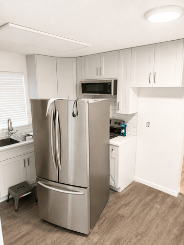Coquitlam apartment for rent - A kitchen with a stainless steel refrigerator and white cabinets.