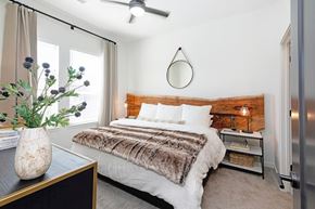 Broomfield apartment for rent - A bedroom with a bed, a vase with flowers, and a ceiling fan  at Bridges at Flatiron, Broomfield, 80021.