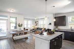 Arden apartment for rent - A modern kitchen with a wooden table and chairs, a bench, and a large island with a sink.