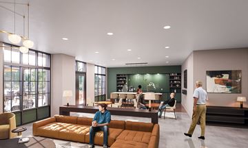 Charlotte apartment for rent - A man in a blue shirt is sitting on a brown couch in a modern living room.