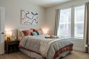 Raleigh apartment for rent - A bedroom with a large bed and a painting on the wall.