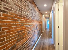 Harrisburg apartment for rent - A long hallway with a brick wall on the left and wooden floors.