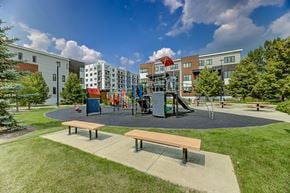 Edmonton townhouse for rent - A playground with a slide and swings in front of a building.