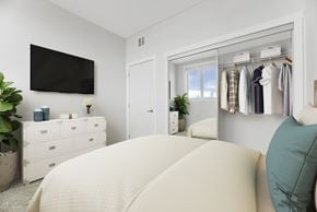 Edmonton townhouse for rent - A bedroom with a large bed and a wardrobe with clothes hanging on it.