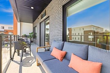 Edmonton townhouse for rent - A balcony with a grey couch and orange pillows.