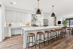Minneapolis townhouse for rent - A kitchen with white cabinets and a white island with four stools.