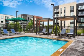 Shoreview apartment for rent - A swimming pool surrounded by chairs and a fence in front of apartment buildings.
