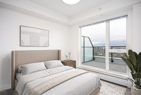 Vancouver apartment for rent - A bedroom with a large bed and a view of the ocean through a glass door at 388 Kaslo East Village.
