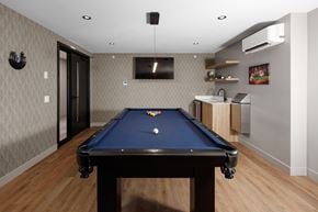 Kelowna apartment for rent - A pool table is in the middle of a room with a television and a bar in the background at The Ambrosi in Kelowna, BC.