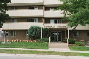 Bradford apartment for rent - Exterior of Bradford Place surrounded by flowers and plant life in Bradford, ON