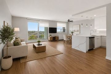 Oakville apartment for rent - A modern living room with a white sofa, a wooden coffee table, and a large window.
