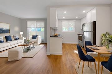 Brockville apartment for rent - A modern living room with a white sofa, a glass coffee table, and a dining table with chairs.