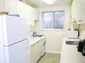 Sarnia apartment for rent - A small kitchen with white appliances and a window with blinds.