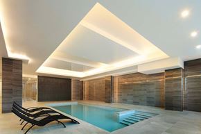 Cote Saint-Luc apartment for rent - A modern indoor swimming pool with a wooden wall and black lounge chairs.