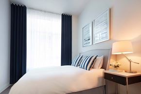 Cote Saint-Luc apartment for rent - A bedroom with a large bed, a nightstand with a lamp, and pictures on the wall.