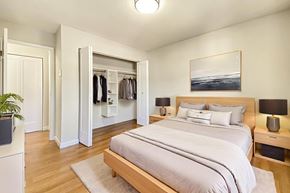 Belleville apartment for rent - A bedroom with a large bed and a wardrobe with clothes hanging on it at Moira Apartments in Belleville, ON