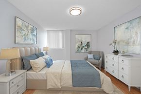 St. Thomas apartment for rent - Sunset Towers primary bedroom with queen bed, two nightstands, dresser and armchair, looking towards window in St. Thomas, ON