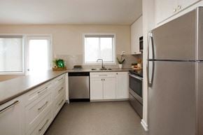 Barrie townhouse for rent - Tamarack Woods Sleek modern kitchen with spotless counters, a fridge, sink, oven and washing machine. Easy view of the outdoor patio through the window and door in Barrie, ON