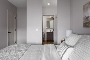 Kelowna apartment for rent - A bedroom with a large bed and a painting on the wall at The Ambrosi in Kelowna, BC.
