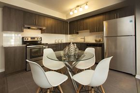 North York apartment for rent - Towns on the Ravine Dining room with white chairs and three brass pine cones as a centerpiece