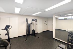 North York apartment for rent - A gym room with a treadmill, a weight machine, and a squat rack.
