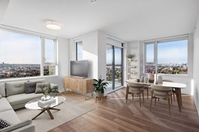 Vancouver apartment for rent - A modern living room with a grey sofa, a wooden cabinet, a glass table, and a view of the city at Yarrow and Aster East Village Apartments in Vancouver.