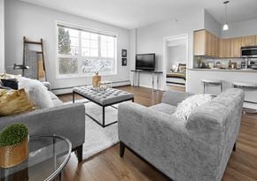 Edmonton apartment for rent - A grey couch sits in a living room with a glass table in front of it.