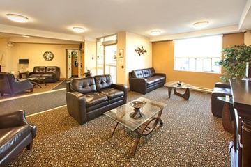 Sarnia apartment for rent - A living room with brown leather furniture and a patterned carpet.