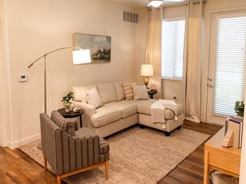 North Logan townhouse for rent - A living room with a grey striped armchair, a white sofa, and a small table with a plant on it.