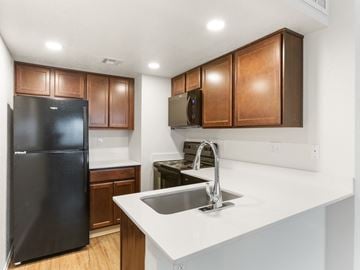 Tucson apartment for rent - A kitchen with a black refrigerator and brown cabinets.
