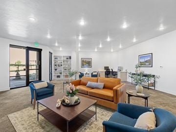 Idaho Falls apartment for rent - A living room with a brown sofa, blue armchair, and a coffee table with a vase of flowers on it.