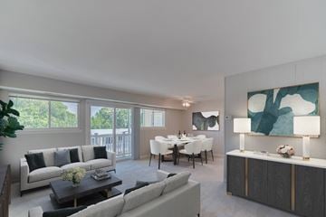 District Heights apartment for rent - A modern living room with a grey sofa, a coffee table, a dining table with chairs, and a large painting on the wall.