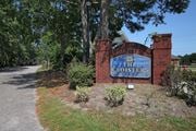 Myrtle Beach apartment for rent - The entrance to The Cloisters with a blue sign on a brick wall. The Cloisters Apartments, 902 67th Avenue North, Myrtle Beach, SC